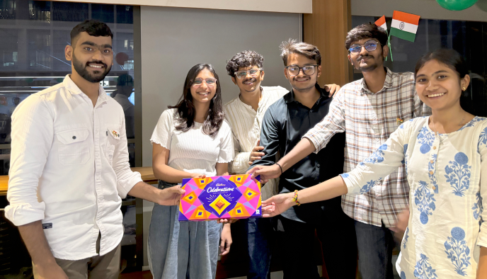 Team members celebrating together with a box of sweets