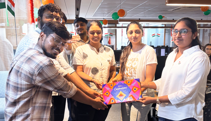 Team members sharing sweets during the Independence Day celebration